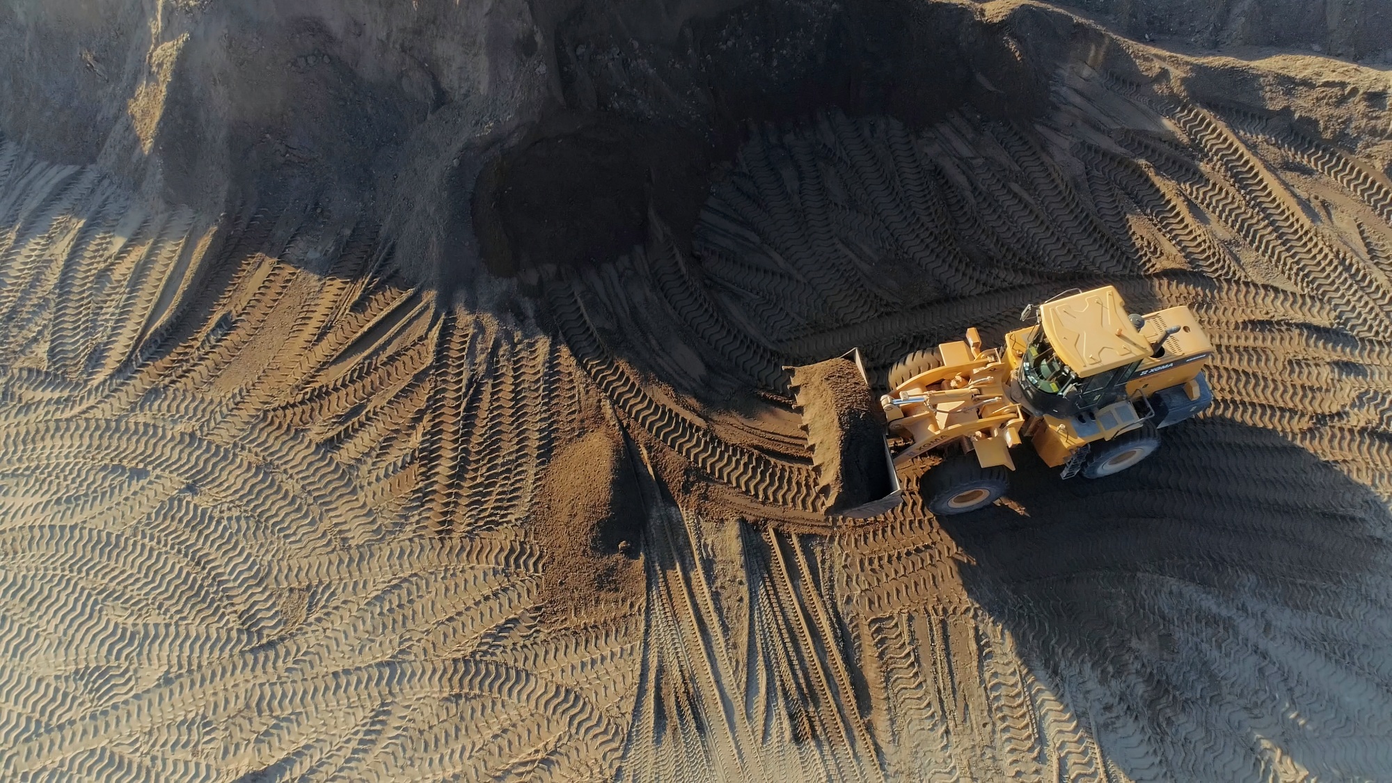 Aerial top view of the machines at work at the construction site. Scene. Bulldozer and truck working