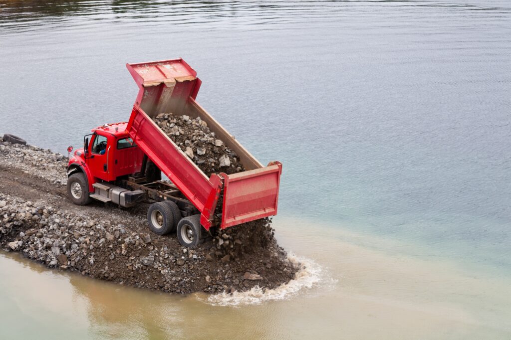 Red dump truck unloading earth fill